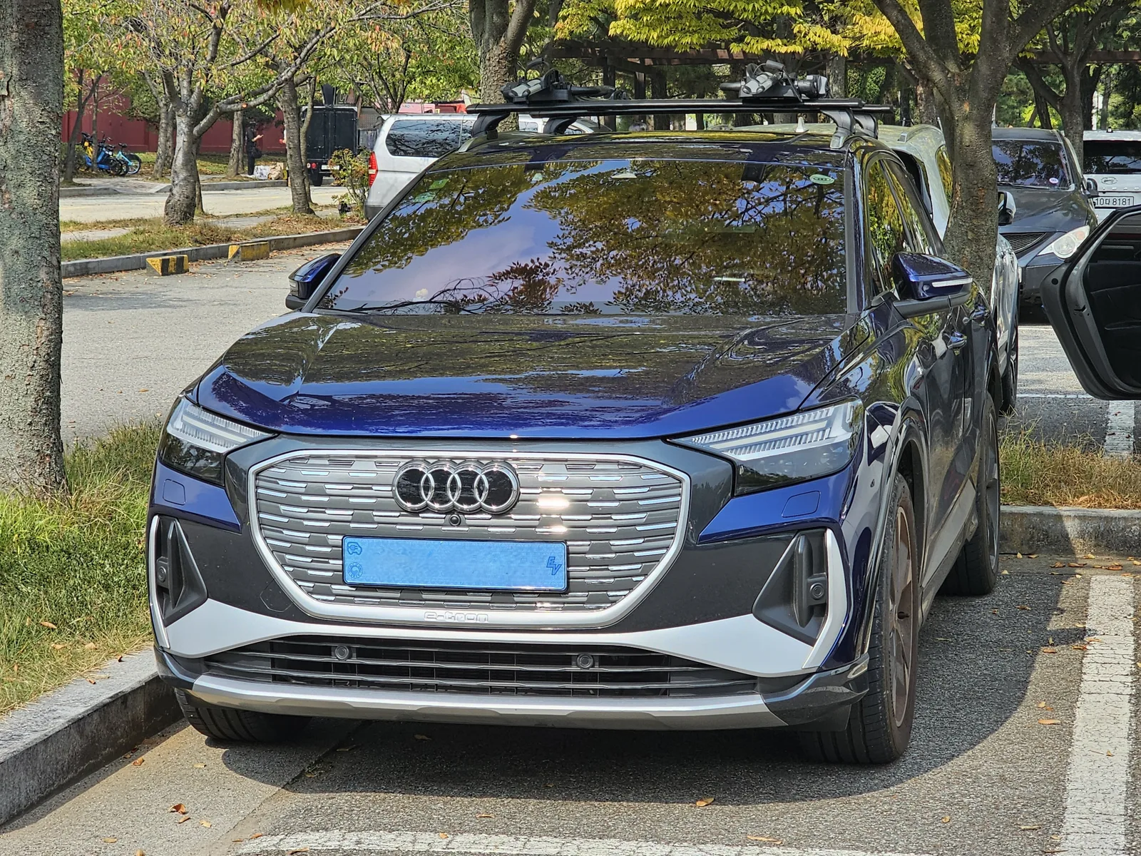Audi Q4 e-tron bleu Navarra vu de face sur un parking, SUV électrique allemand comparé au BMW iX1 et au Mercedes GLA