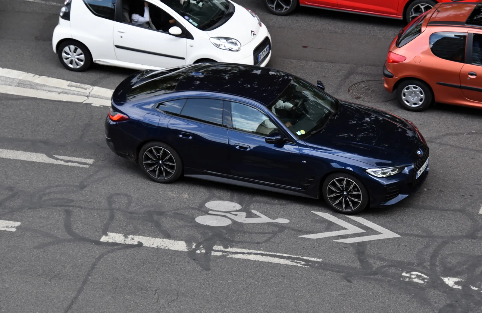 BMW i4 2026 vue de dessus dans une rue parisienne, couleur bleue en circulation urbaine