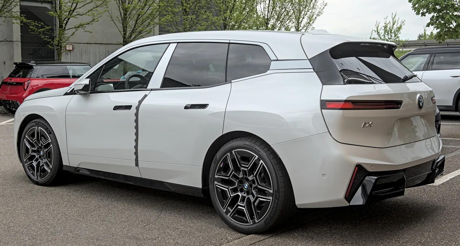 BMW iX 2026 vue de profil et trois quarts arrière SUV électrique blanc badge iX visible stationné en extérieur