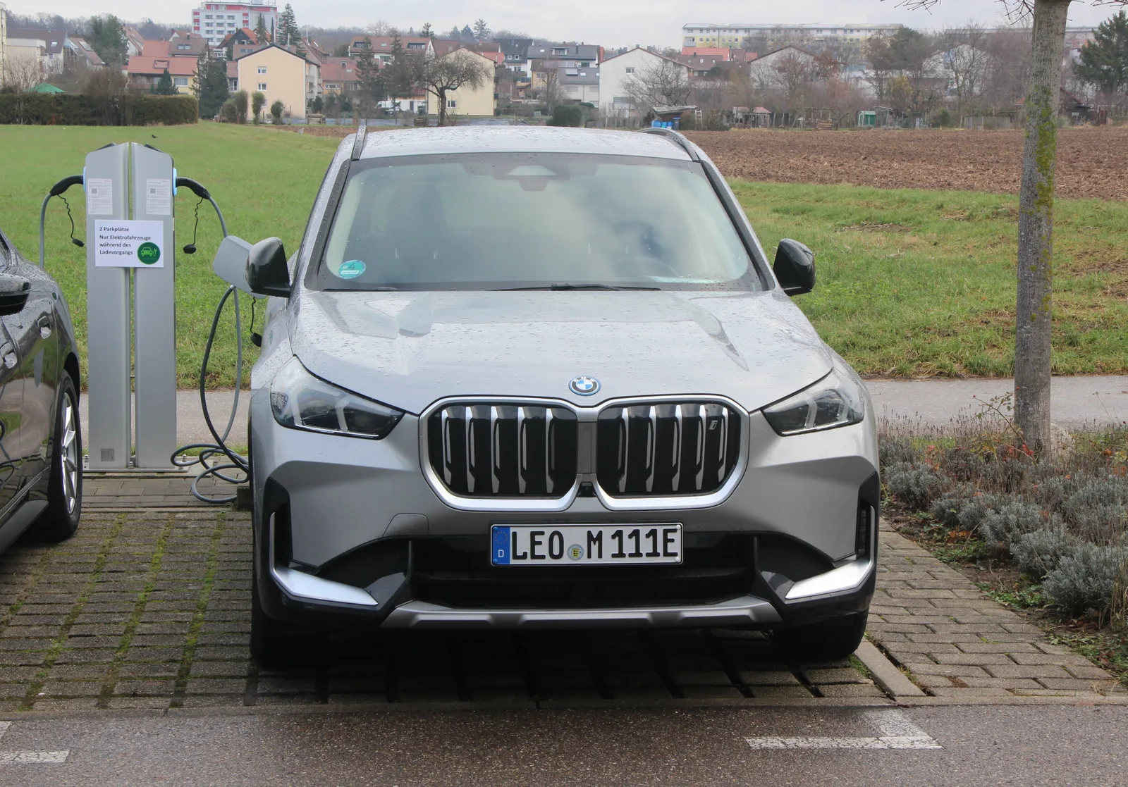 BMW iX1 2026 gris en charge sur une borne de recharge rapide — SUV électrique BMW branché recharge DC