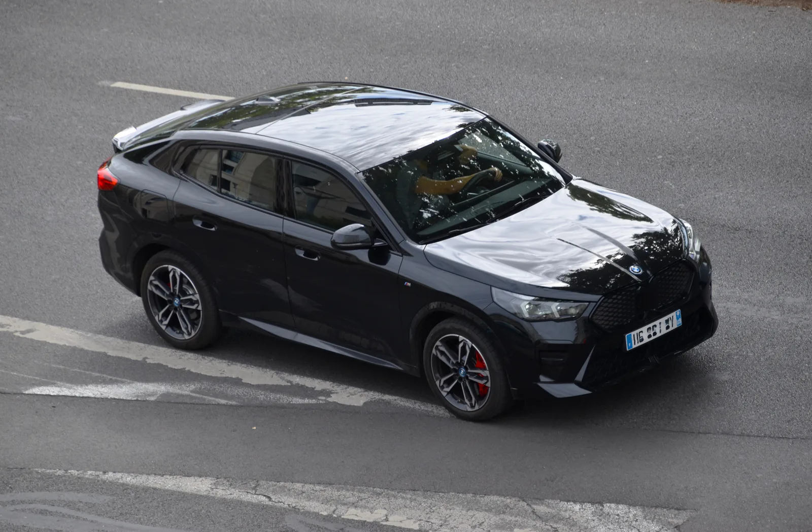 BMW iX2 xDrive30 (U10, 2024) en noir vue surélevée — cockpit conducteur orienté, lignes sportives de la carrosserie SAC et silhouette imposante
