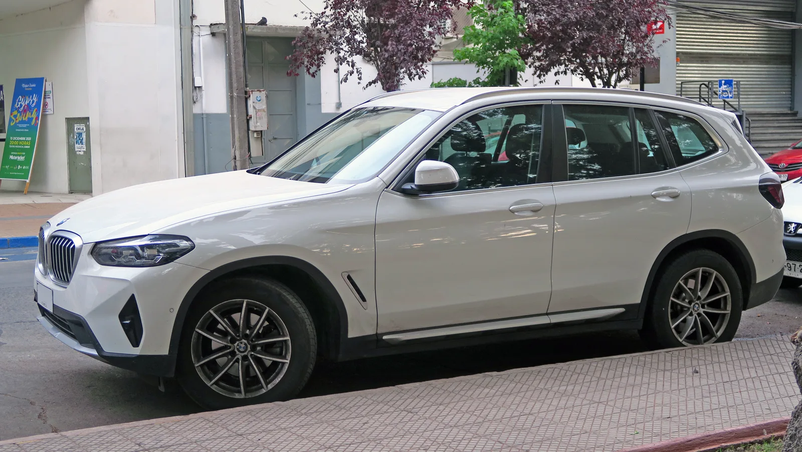 BMW X3 xDrive30e 2024 gris vue 3/4 arrière en ville — PHEV avec ~50 km d'autonomie électrique WLTP