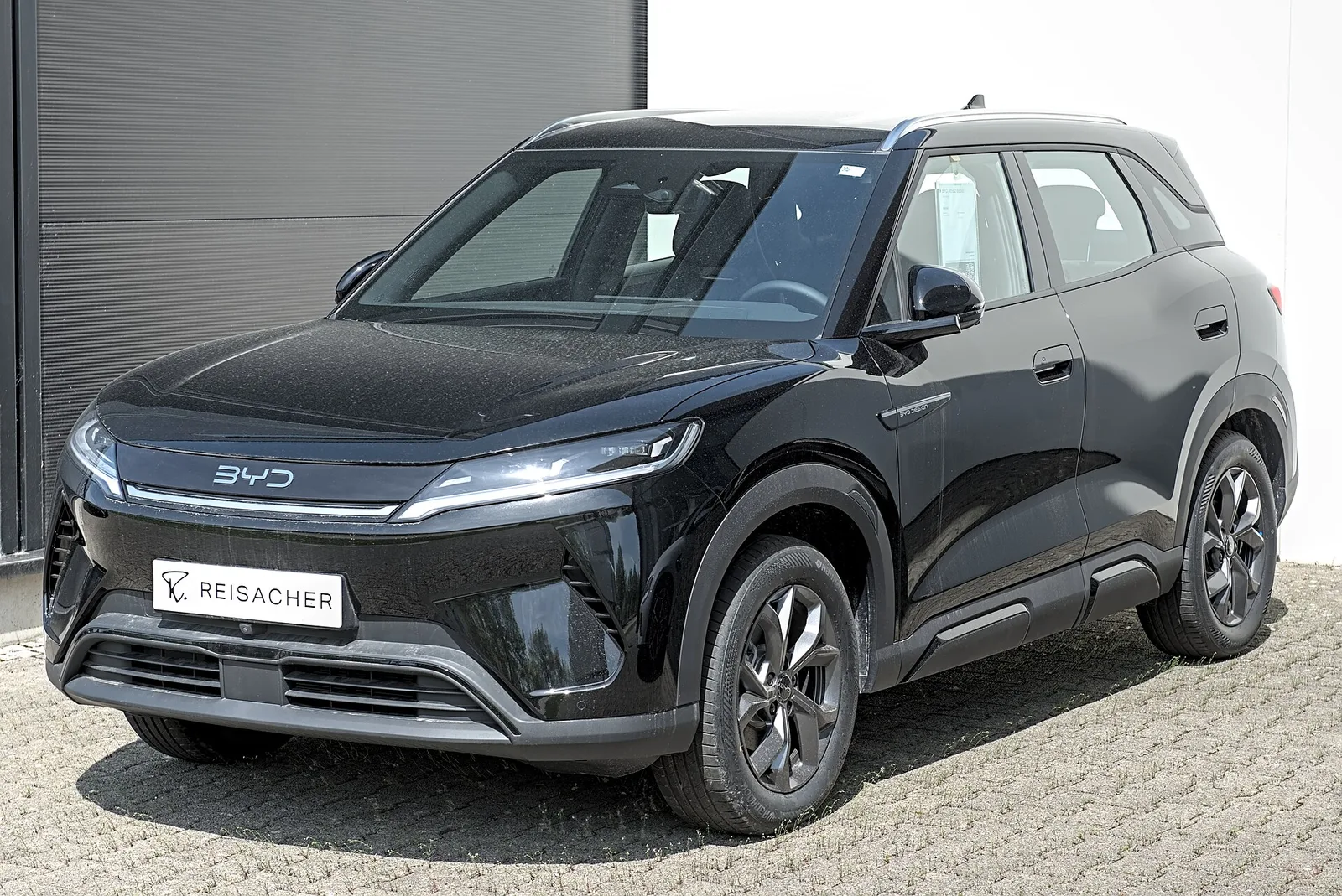 BYD Atto 2 noir vu de trois quarts avant garé devant une concession, calandre fermée et signature lumineuse fine