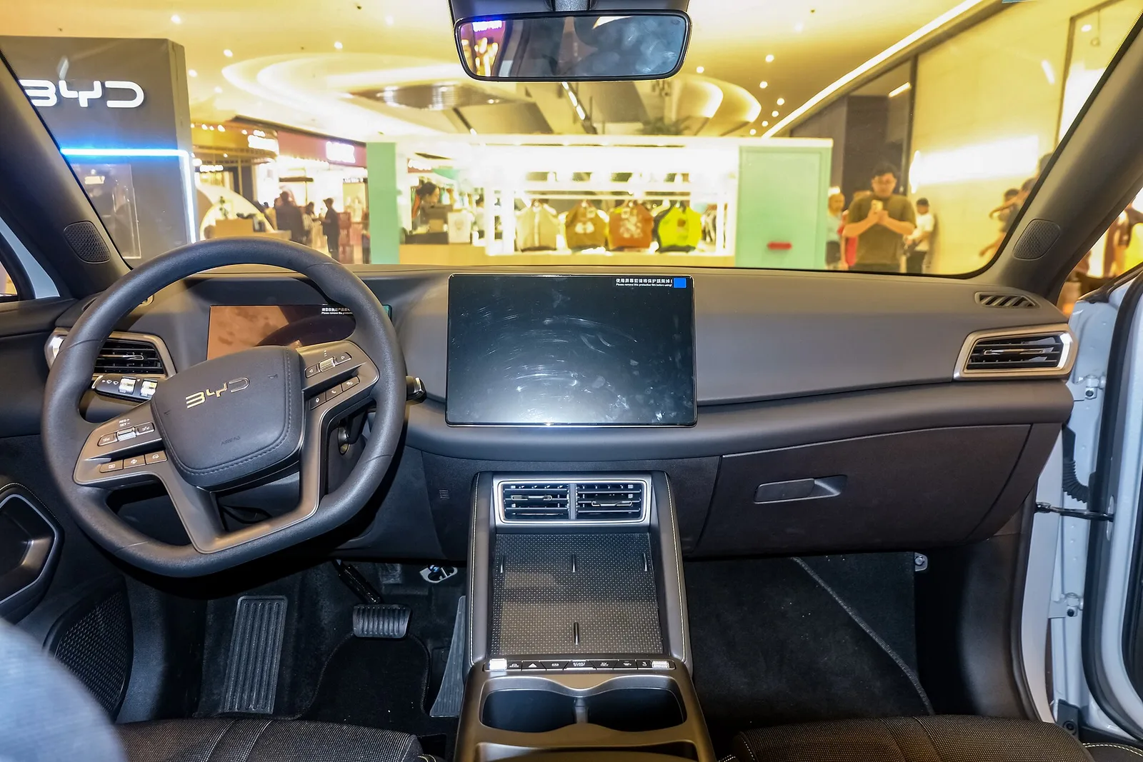 Planche de bord du BYD Atto 2 avec volant à trois branches, écran central flottant et console centrale avec recharge par induction