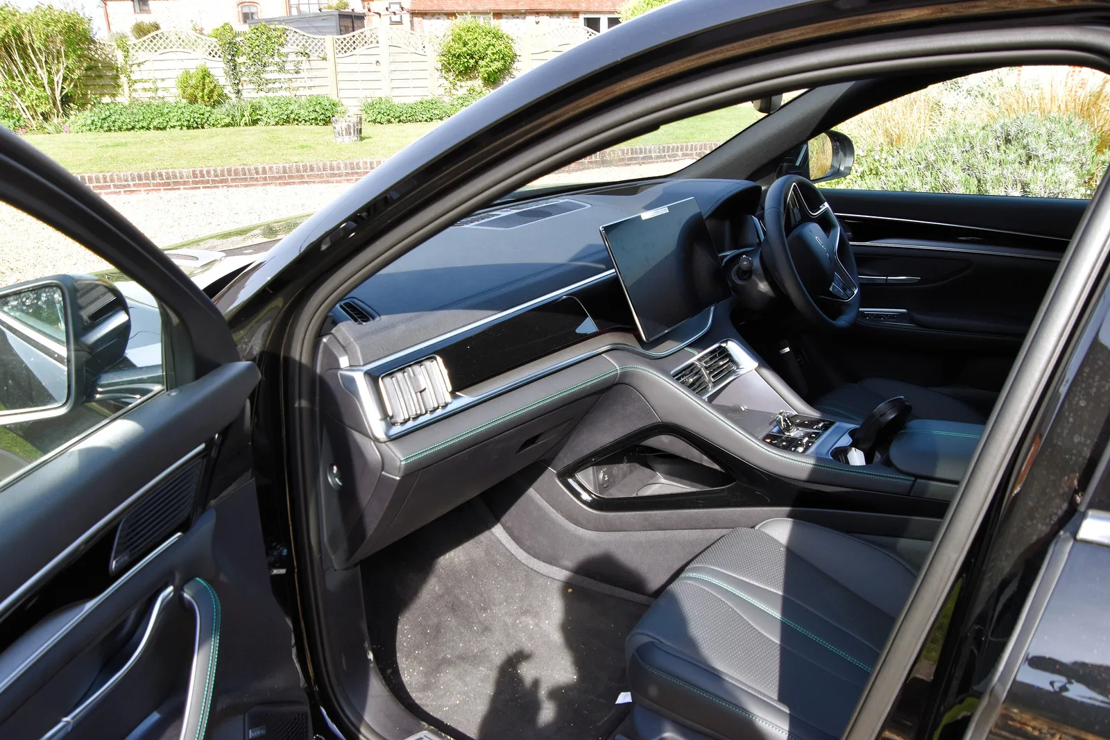 Planche de bord du BYD Seal U DM-i avec grand écran central tactile et sièges en cuir noir vus depuis la portière conducteur