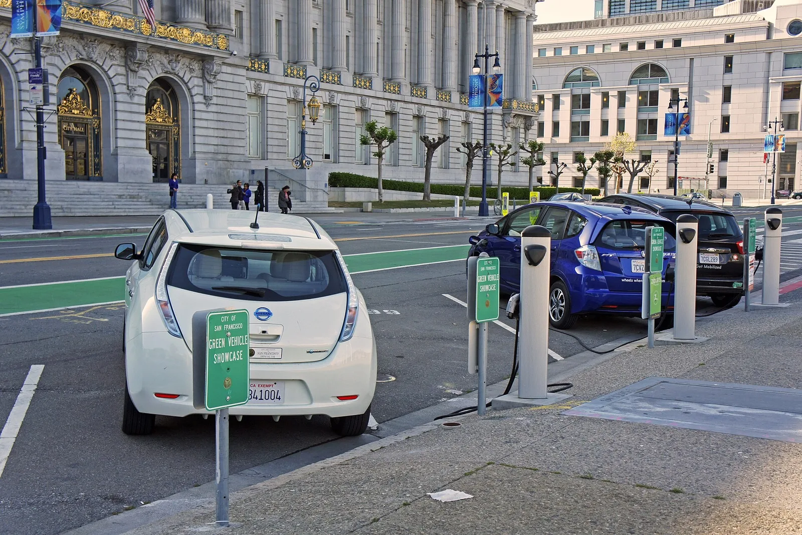 Deux Nissan Leaf en recharge sur des bornes en bord de rue devant un bâtiment public
