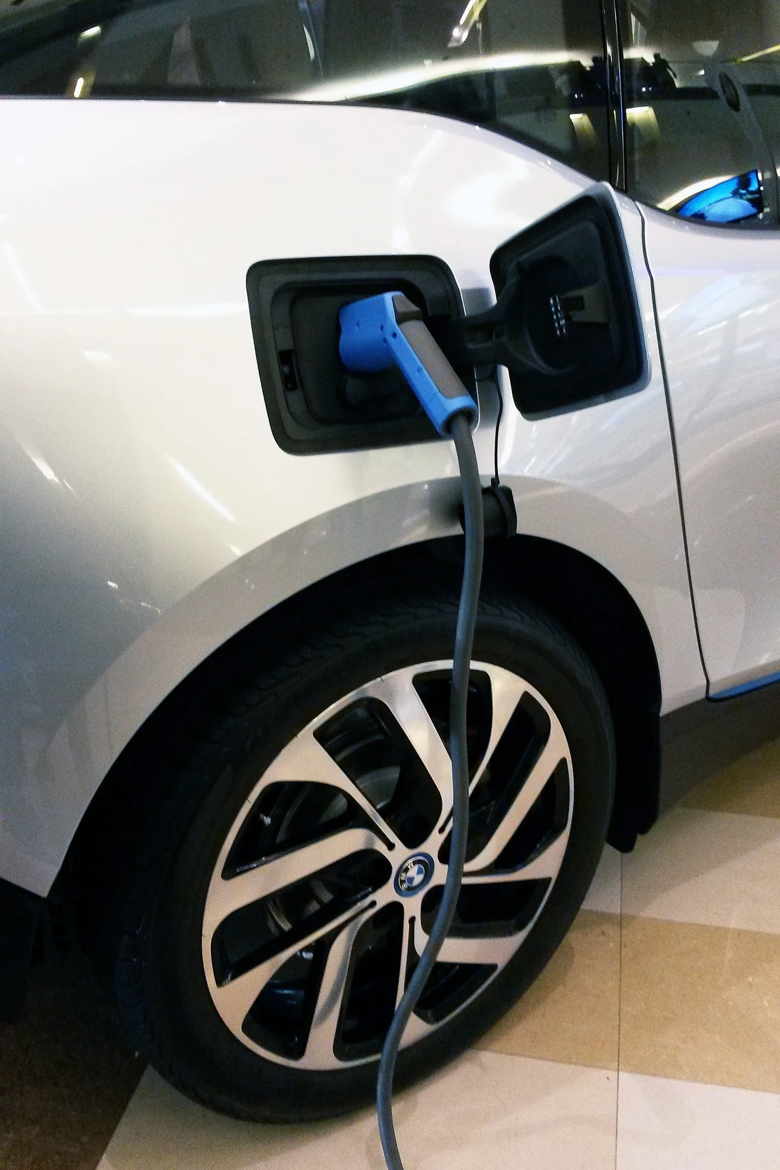 Prise de charge d'une BMW i3 argentée branchée sur son câble de recharge bleu