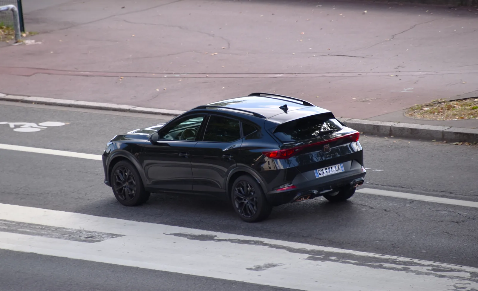 Cupra Formentor 2022-2026 vue arrière surélevée — feux arrière triangulaires rouges signature Cupra sur asphalte humide, silhouette coupé reconnaissable