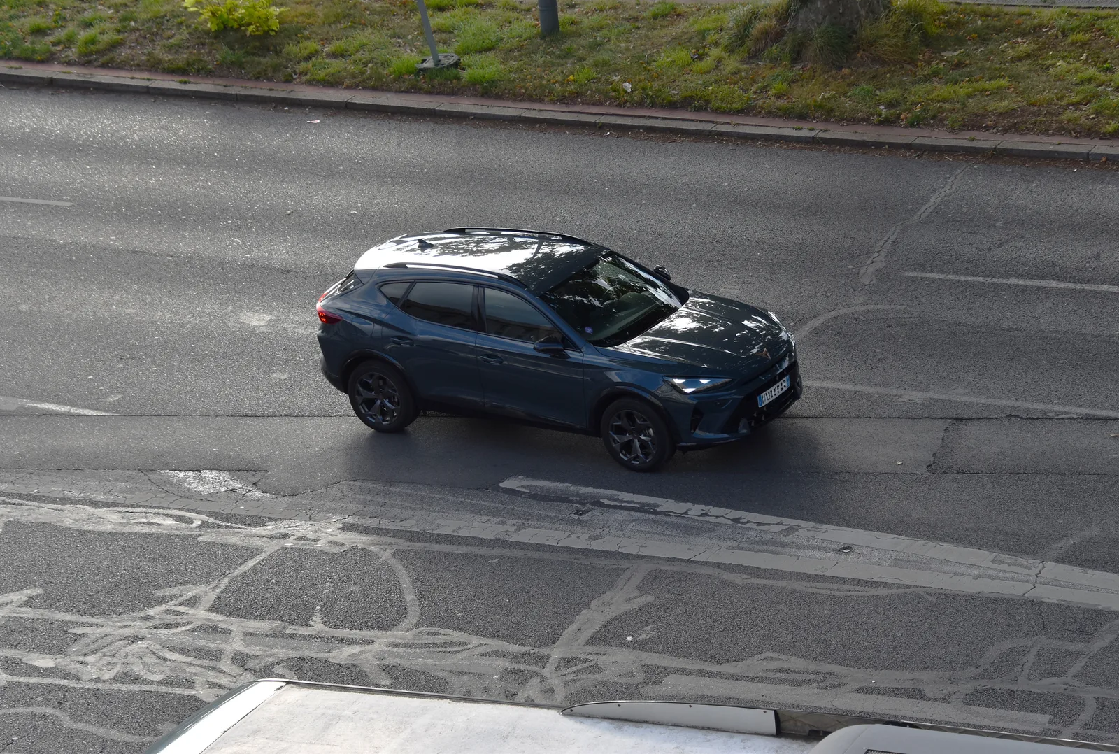 Cupra Formentor VZ 2024 en bleu foncé vue du dessus en circulation — lignes aérodynamiques tendues et silhouette coupé-SUV caractéristique