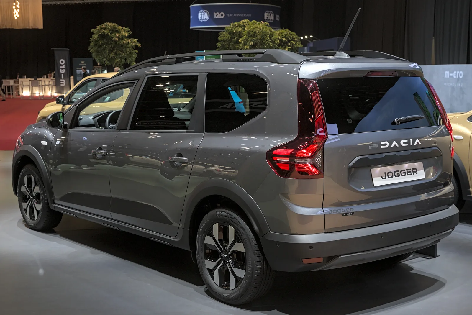 Dacia Jogger 2026 vue 3/4 arrière au salon GIMS, coloris gris magistral, finition Extreme avec barres de toit