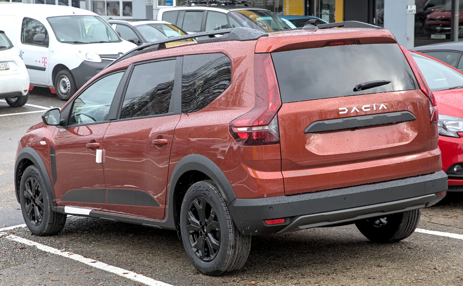 Dacia Jogger 2026 vue de profil, coloris rouge garnets, 7 places, parqué en ville