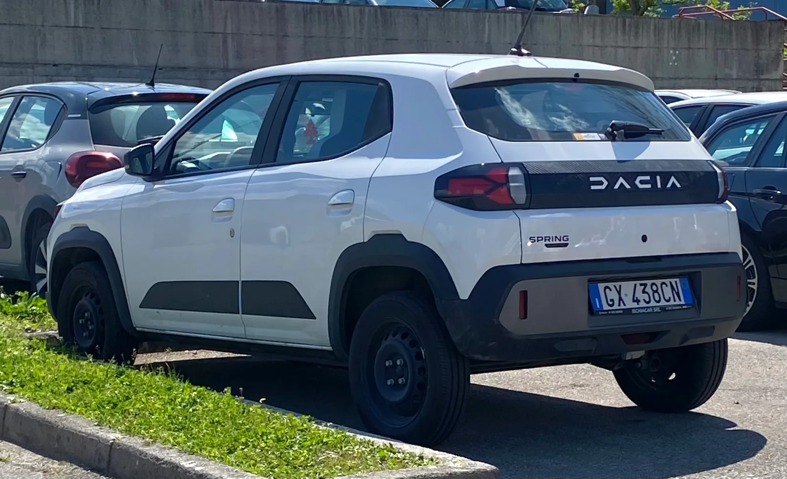 Dacia Spring 2025 blanche vue de trois quarts arrière sur un parking, citadine électrique parmi les plus sobres