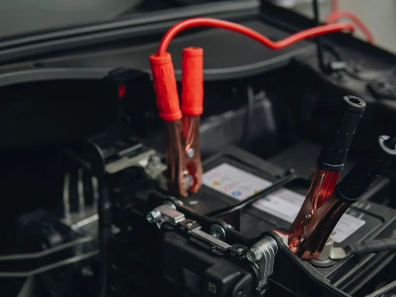 Câbles de démarrage connectés sur une batterie de voiture — procédure de dépannage avec booster pour diagnostiquer un démarreur défaillant