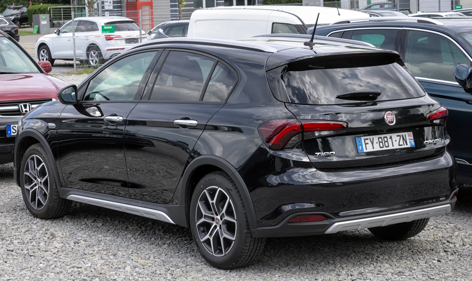Fiat Tipo Cross noire 2026 vue trois quarts arrière hayon parking gravier