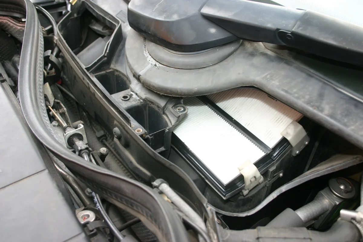 Filtre habitacle visible dans son logement sous le capot d'une Mercedes, boîtier ouvert