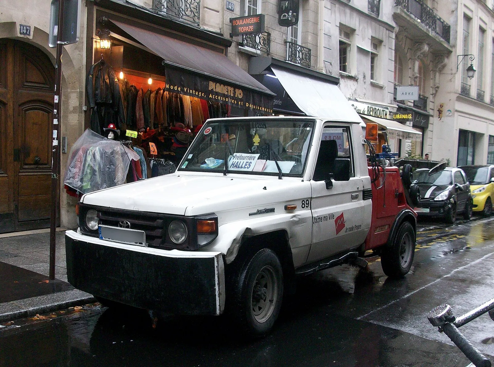 Dépanneuse de la préfourrière des Halles à Paris garée dans une rue commerçante, flèche de levage à l'arrière