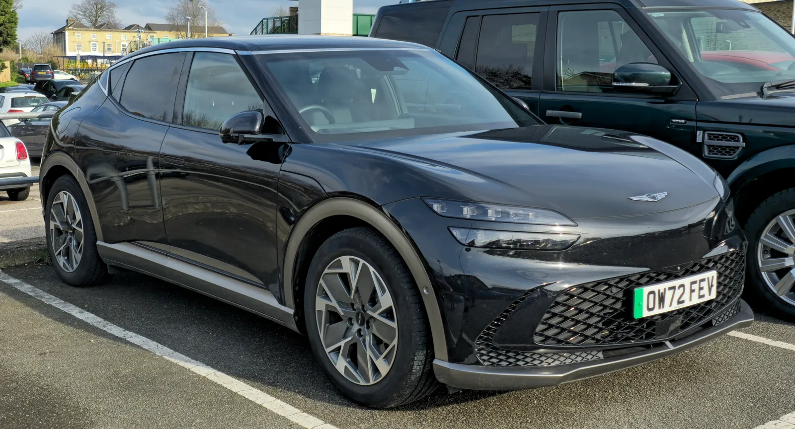 Genesis GV60 2026 vue 3/4 avant SUV électrique premium noir en parking