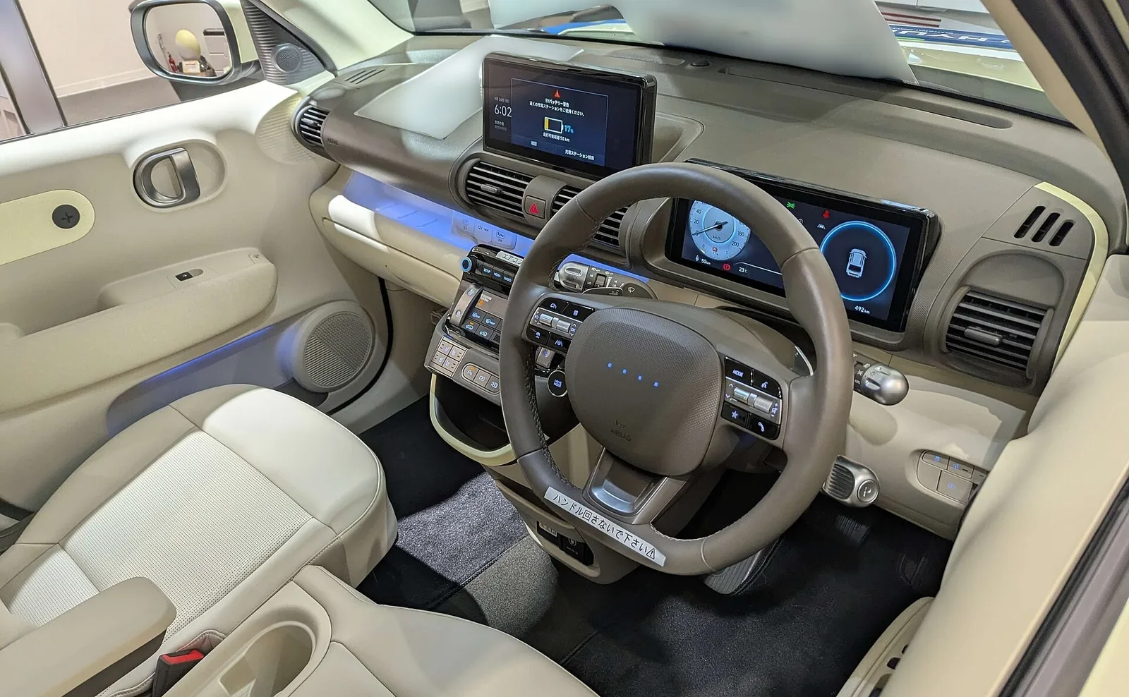 Intérieur clair d'un Hyundai Inster électrique avec volant, écrans et sièges avant, petite électrique commandable en ligne via Click to Buy