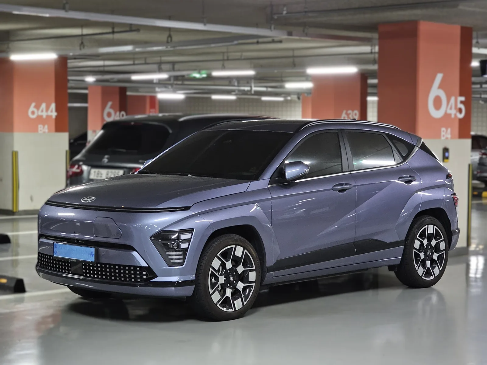 Hyundai Kona Electric Inspiration 2026 bleu — vue 3/4 arrière, feux LED barre lumineuse