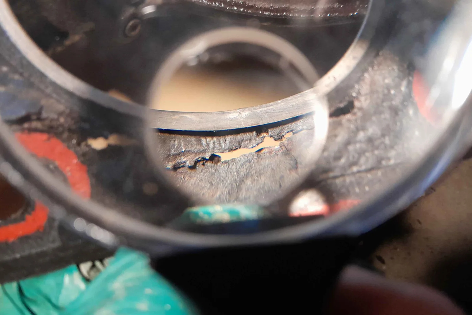 Gros plan au travers d'une loupe sur un joint de culasse fendu et endommagé — fissure transversale visible