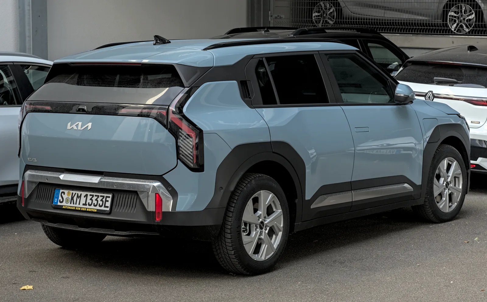 Kia EV3 2026 bleu vue trois quarts arrière SUV électrique compact stationnement urbain