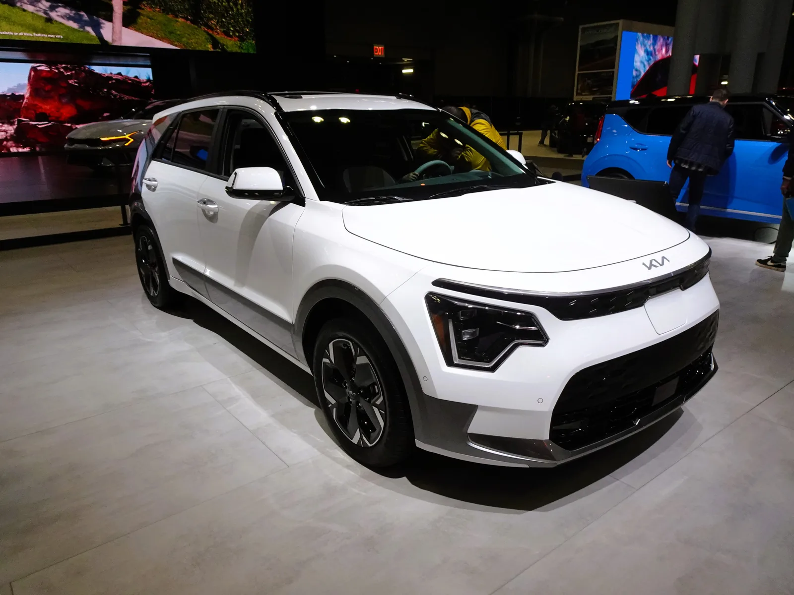 Kia Niro EV 2026 en blanc vue 3/4 avant lors d'un salon automobile
