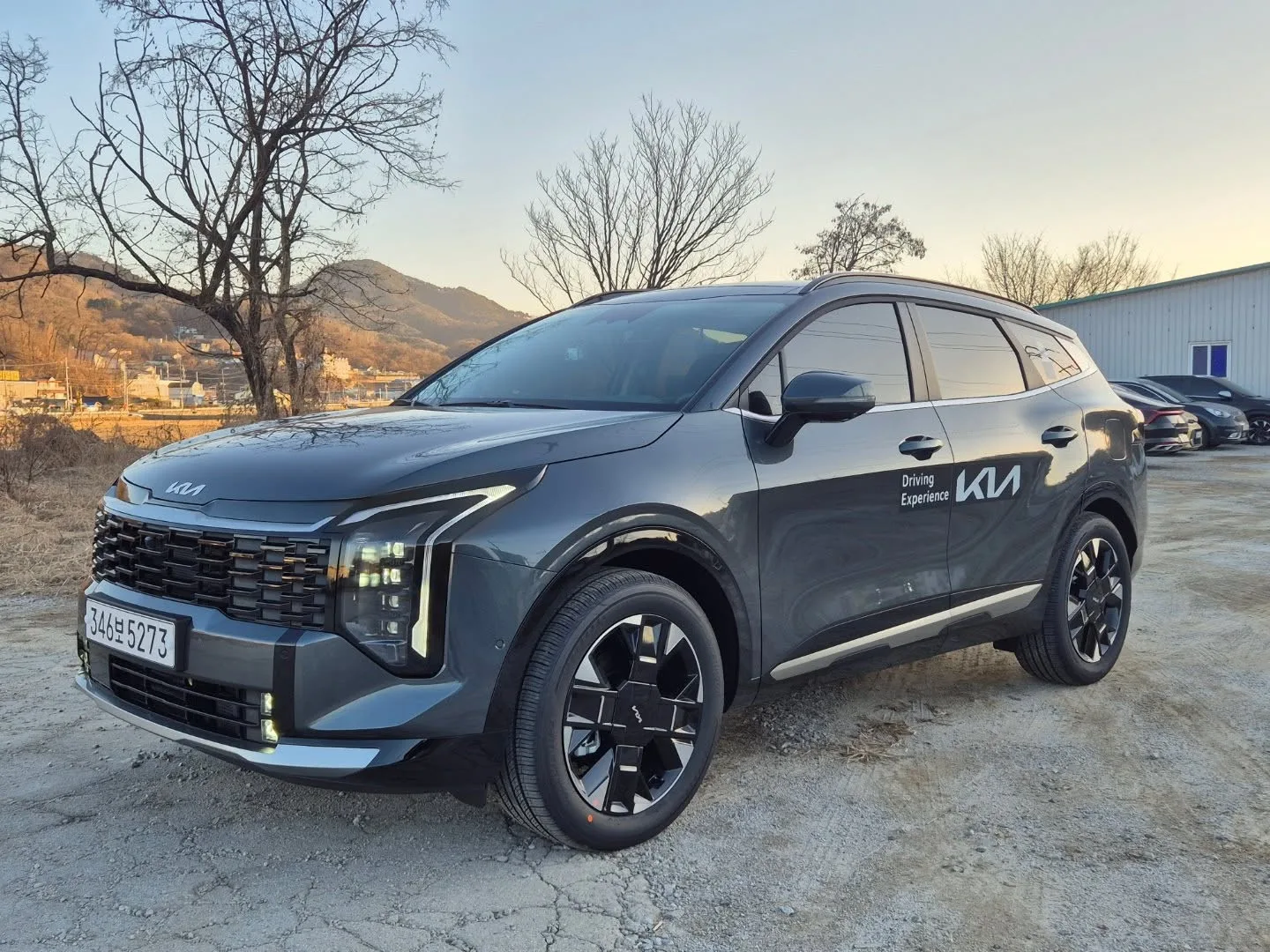 Kia Sportage hybride restylé gris foncé vu de trois quarts avant, SUV familial noté 5 étoiles Euro NCAP avec garantie 7 ans