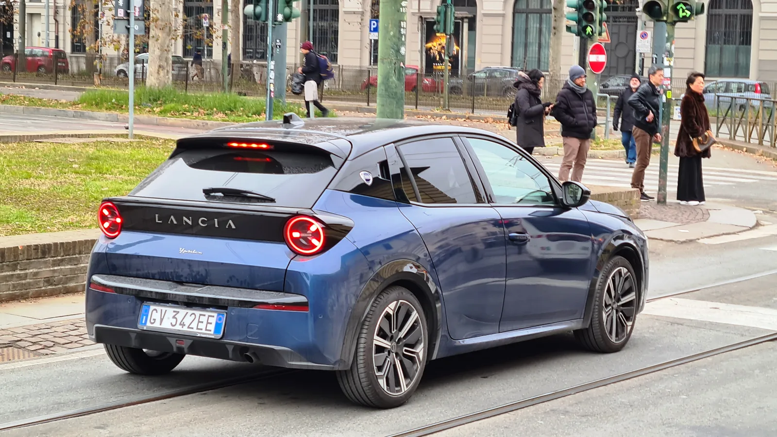 Lancia Ypsilon 2026 vue 3/4 arrière citadine bleue avec logo Lancia visible, scène urbaine à Turin