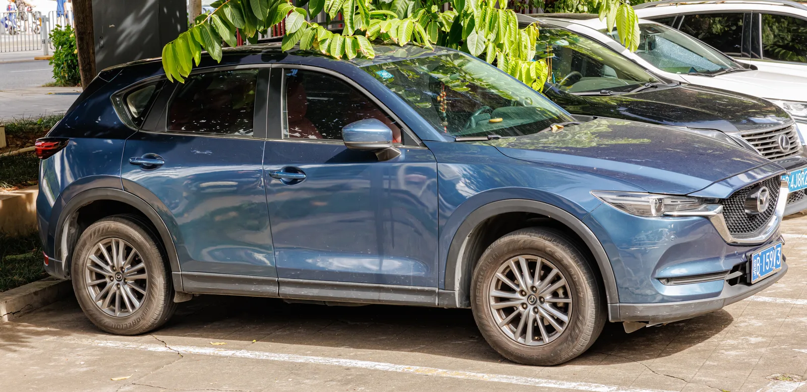 Mazda CX-5 2026 vue de profil, coloris bleu polymétallique, finition Elegance, stationnement urbain
