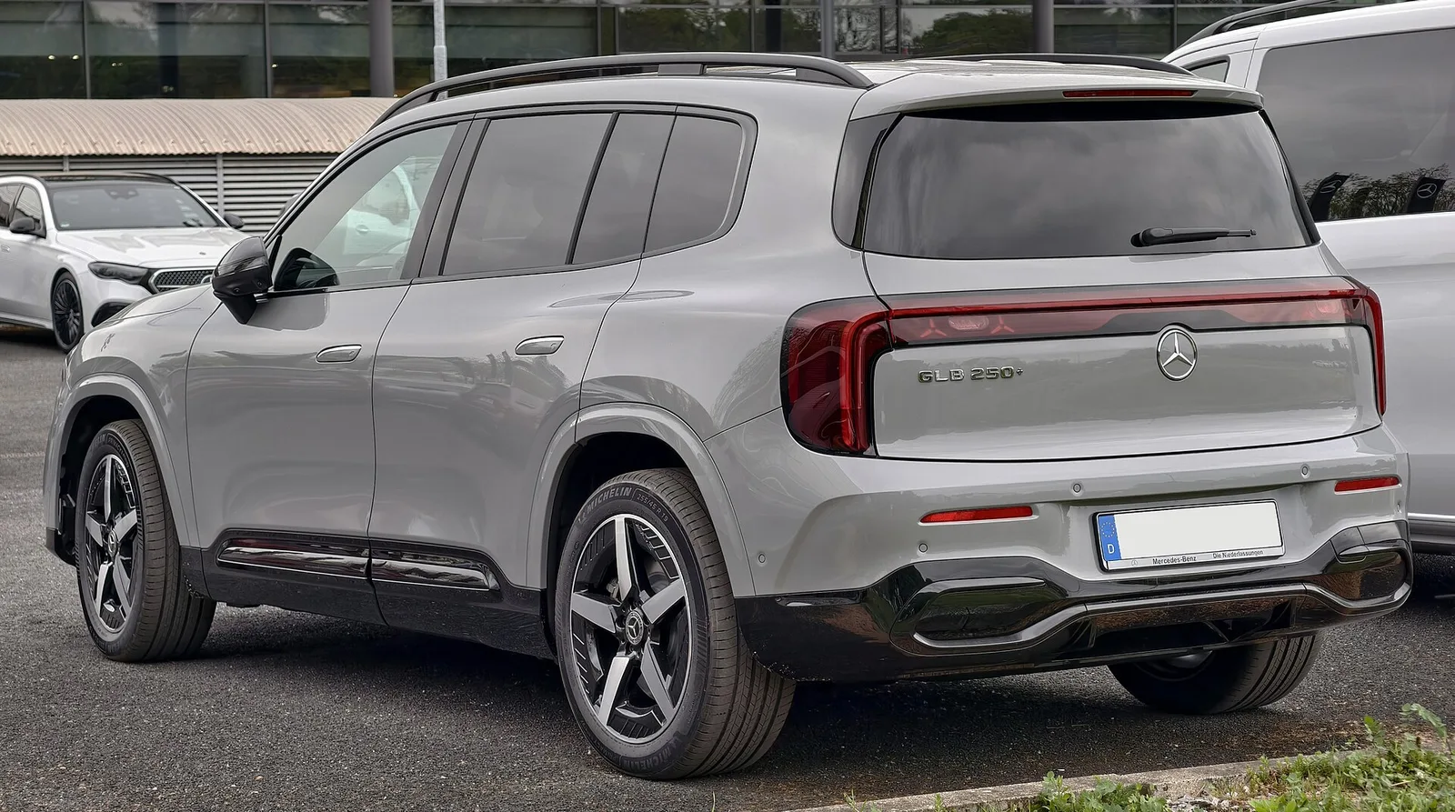 Mercedes GLB 250+ électrique gris vu de trois quarts arrière sur un parking, SUV compact électrique disponible en 7 places