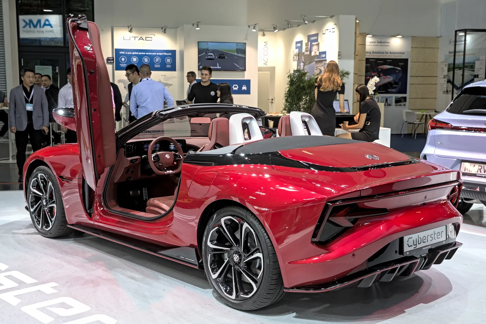 MG Cyberster 2026 vue trois quarts arrière roadster électrique rouge portes papillon ouvertes salon