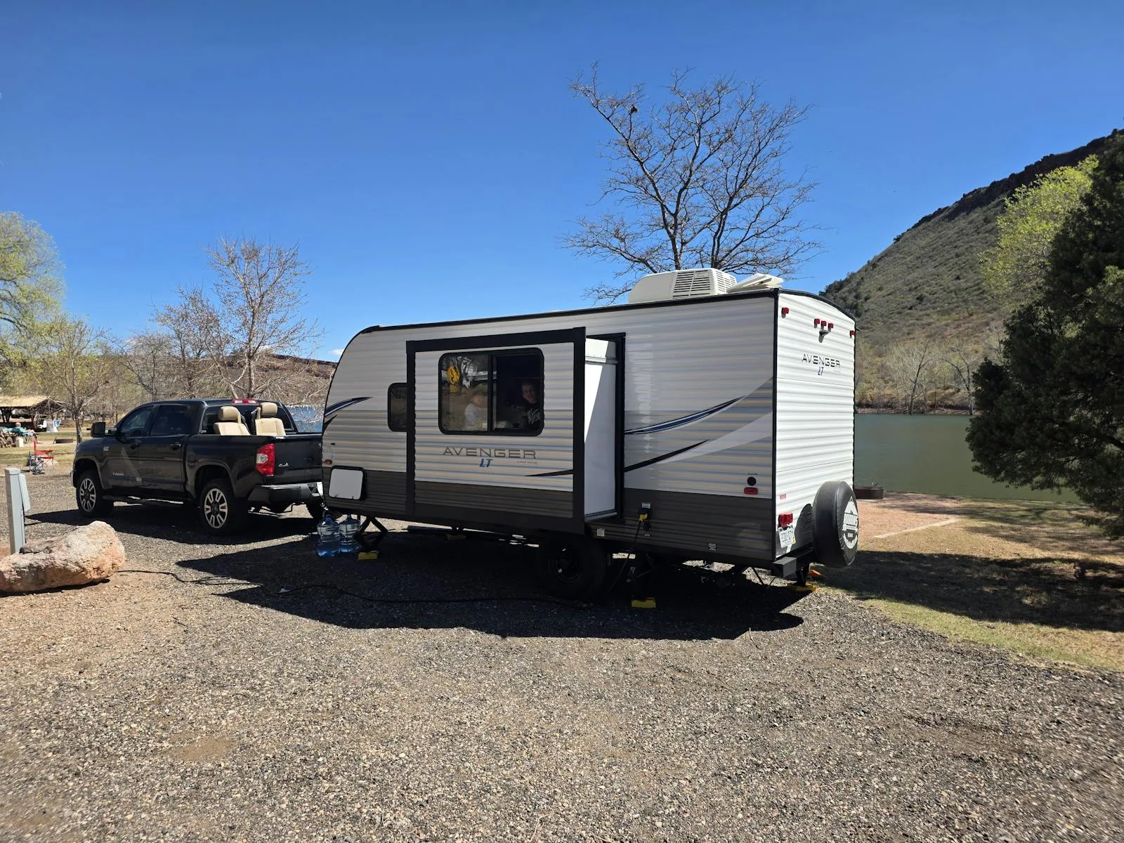 Camionnette tractant une caravane de loisir moderne stationnée en camping face à un lac