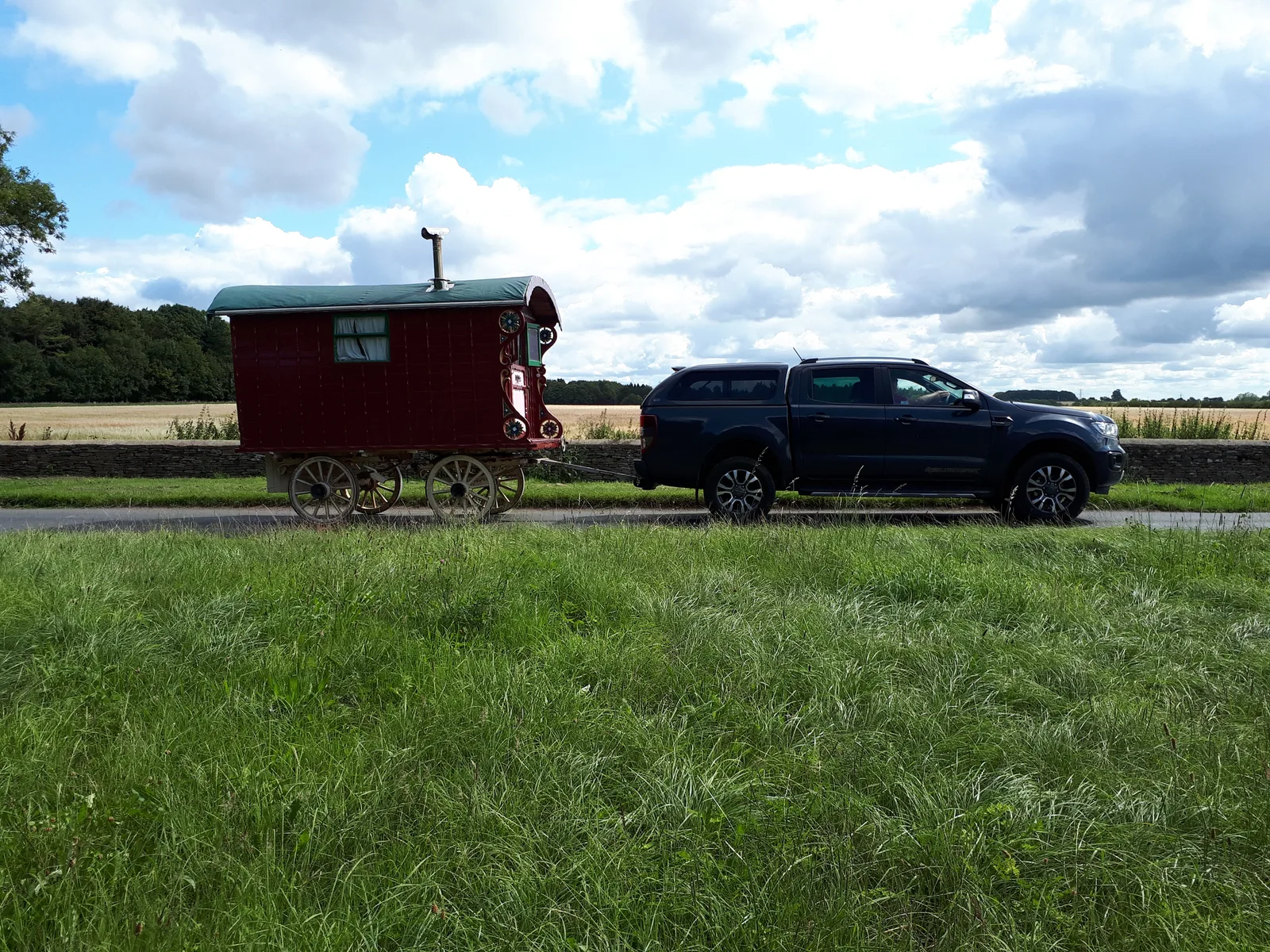 Pickup noir tractant une roulotte traditionnelle sur une route rurale anglaise