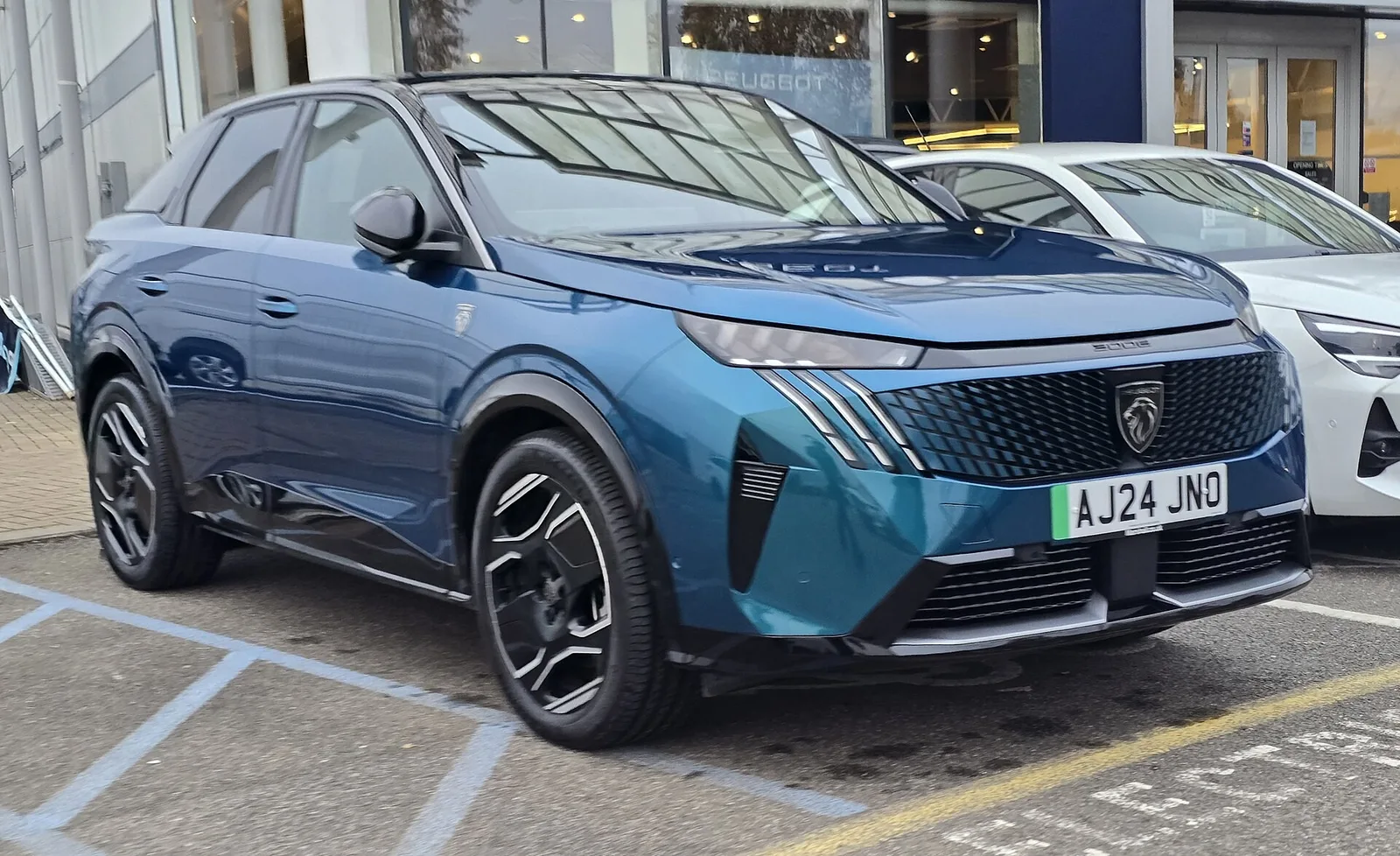 Peugeot e-3008 GT électrique bleu garé sur un parking, SUV à 701 km d'autonomie WLTP en batterie 97 kWh