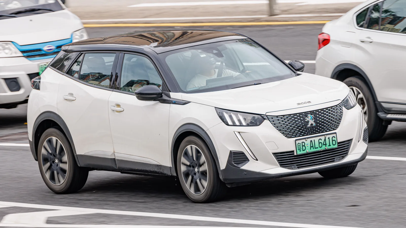 Peugeot e-2008 électrique en blanc, vue 3/4 avant en circulation urbaine