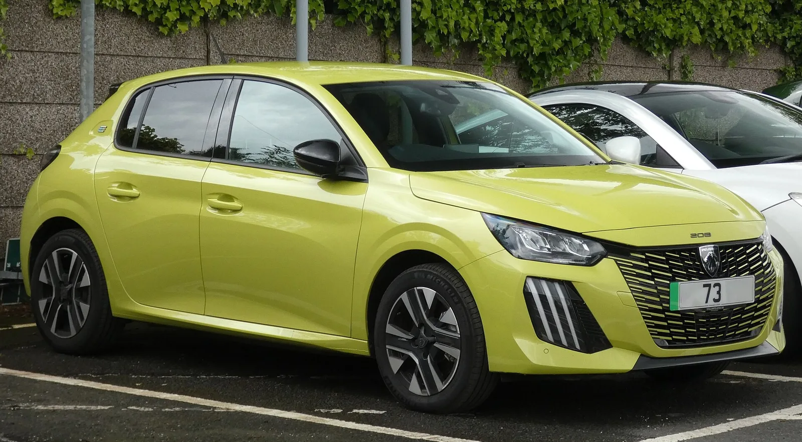 Peugeot e-208 jaune vue de trois quarts avant, citadine électrique dont le coût d'achat dépasse celui de la version essence