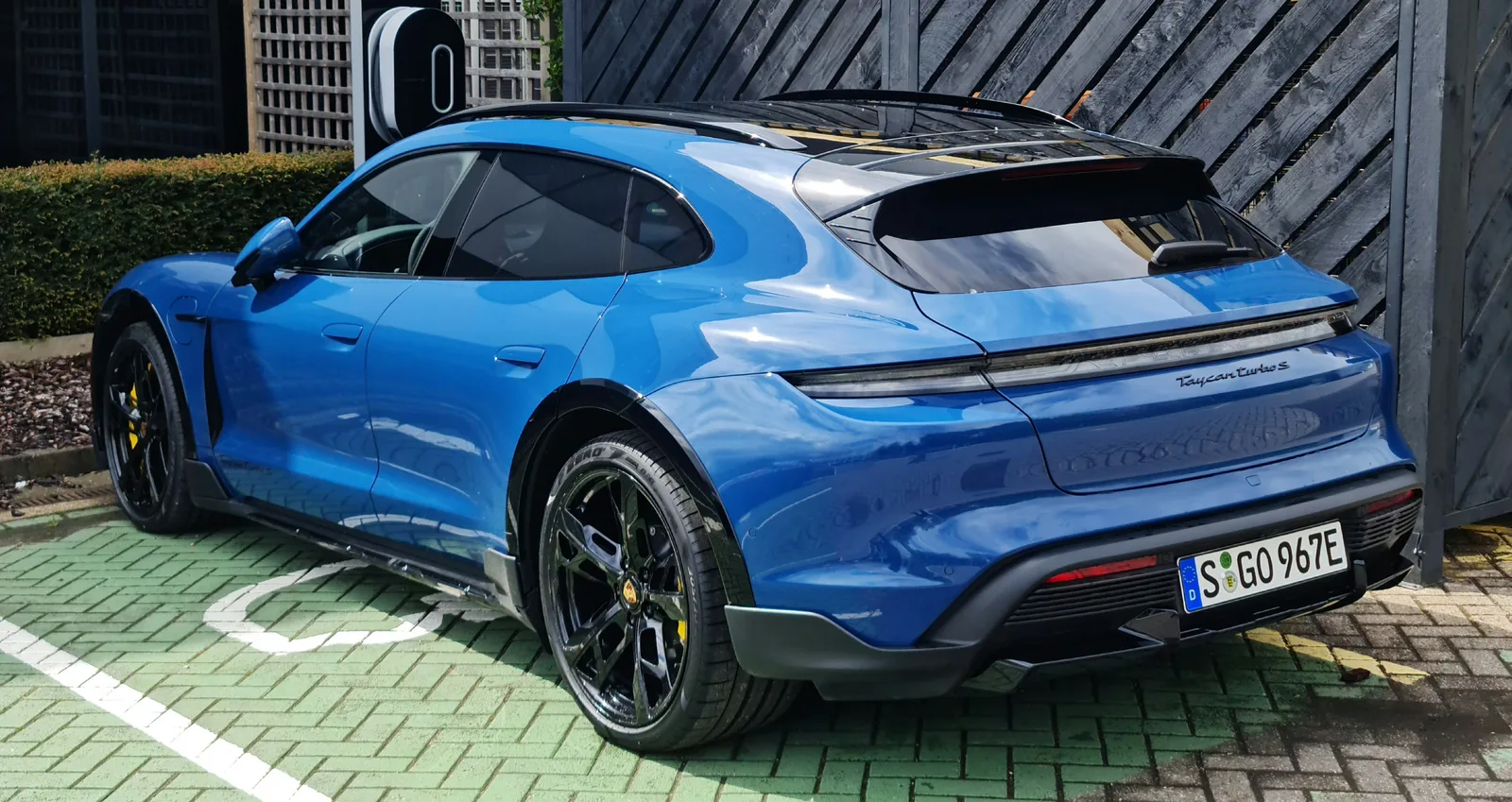 Porsche Taycan Cross Turismo 2026 bleue vue arrière branchée sur borne de recharge électrique