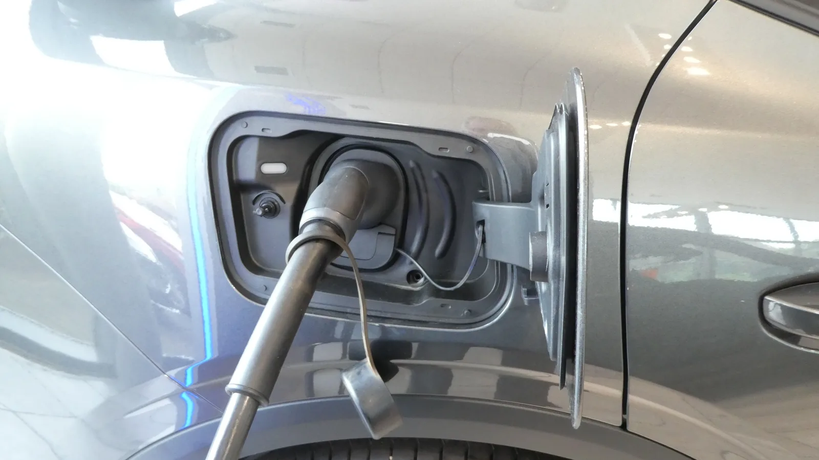 Câble de recharge Type 2 branché sur la prise d'une voiture électrique grise, gros plan sur le connecteur