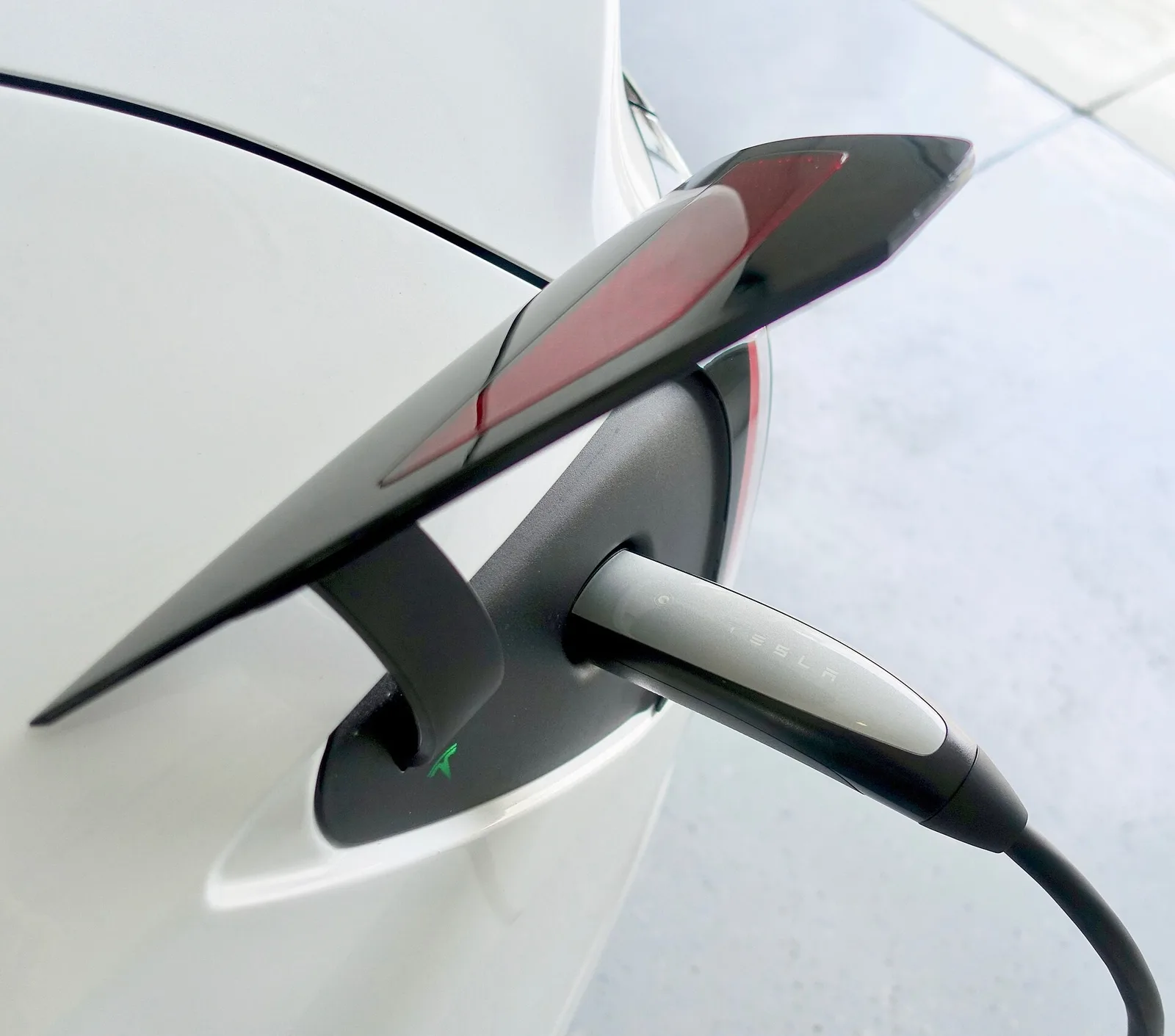 Prise de recharge d'une Tesla Model 3 blanche, branchée sur son câble de charge