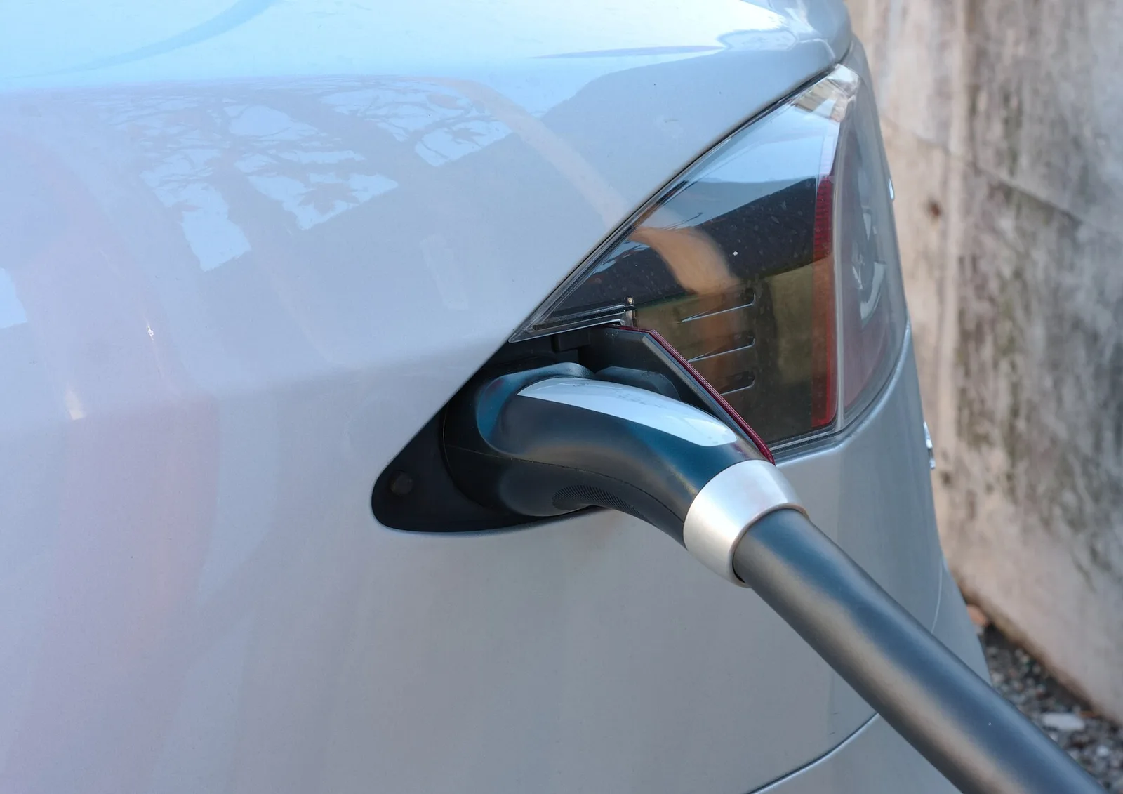 Prise de recharge Type 2 branchée sur une voiture électrique grise, vue rapprochée de la trappe de charge