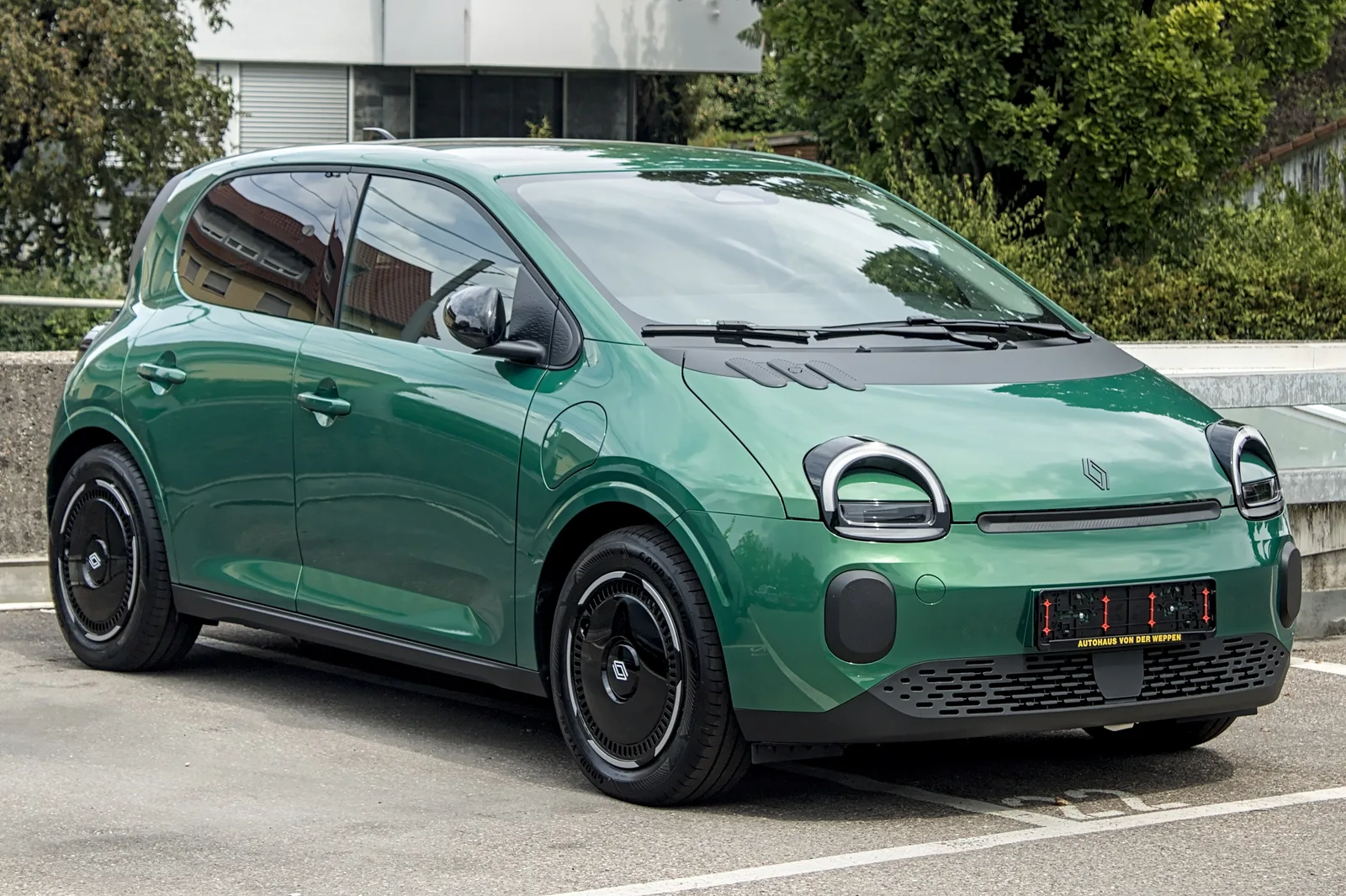 Renault Twingo E-Tech électrique verte vue de trois quarts avant sur un parking, citadine éligible à la prime coup de pouce