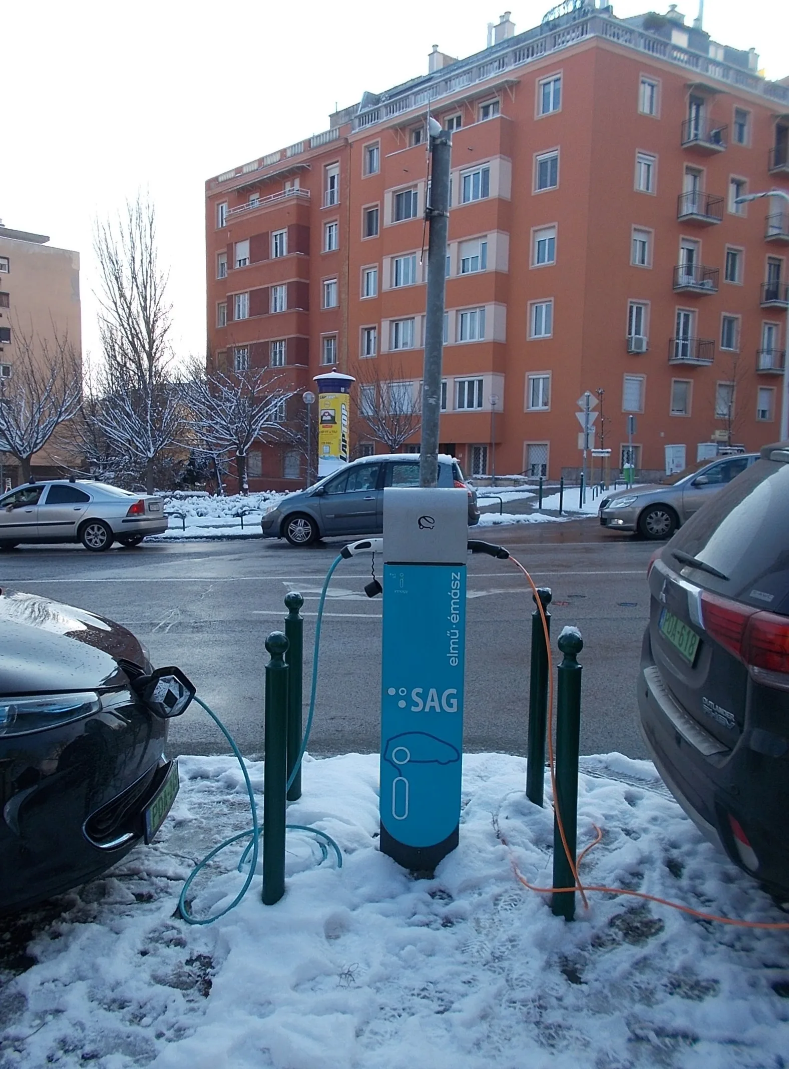 Renault Zoe branchée sur une borne de recharge publique à côté d'un autre véhicule, câble de recharge couvert ou non par l'assurance