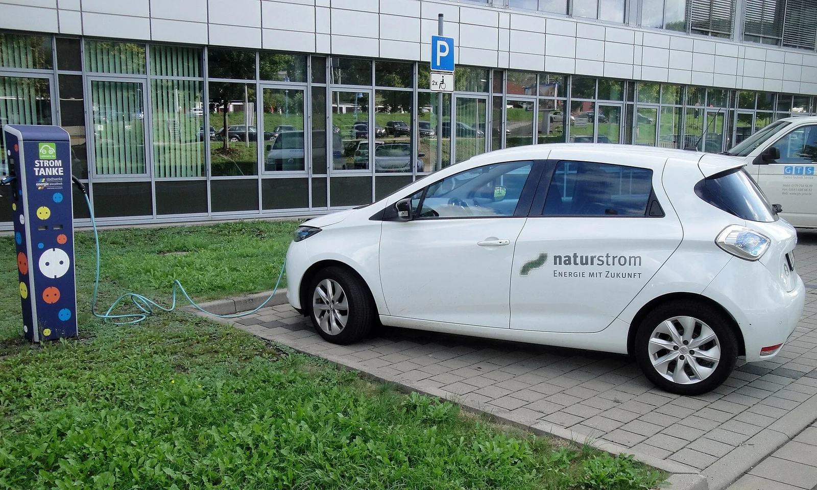 Renault Zoe blanche garée près d'une borne de recharge, petite électrique d'occasion dont l'autonomie dépend de l'état de santé de la batterie