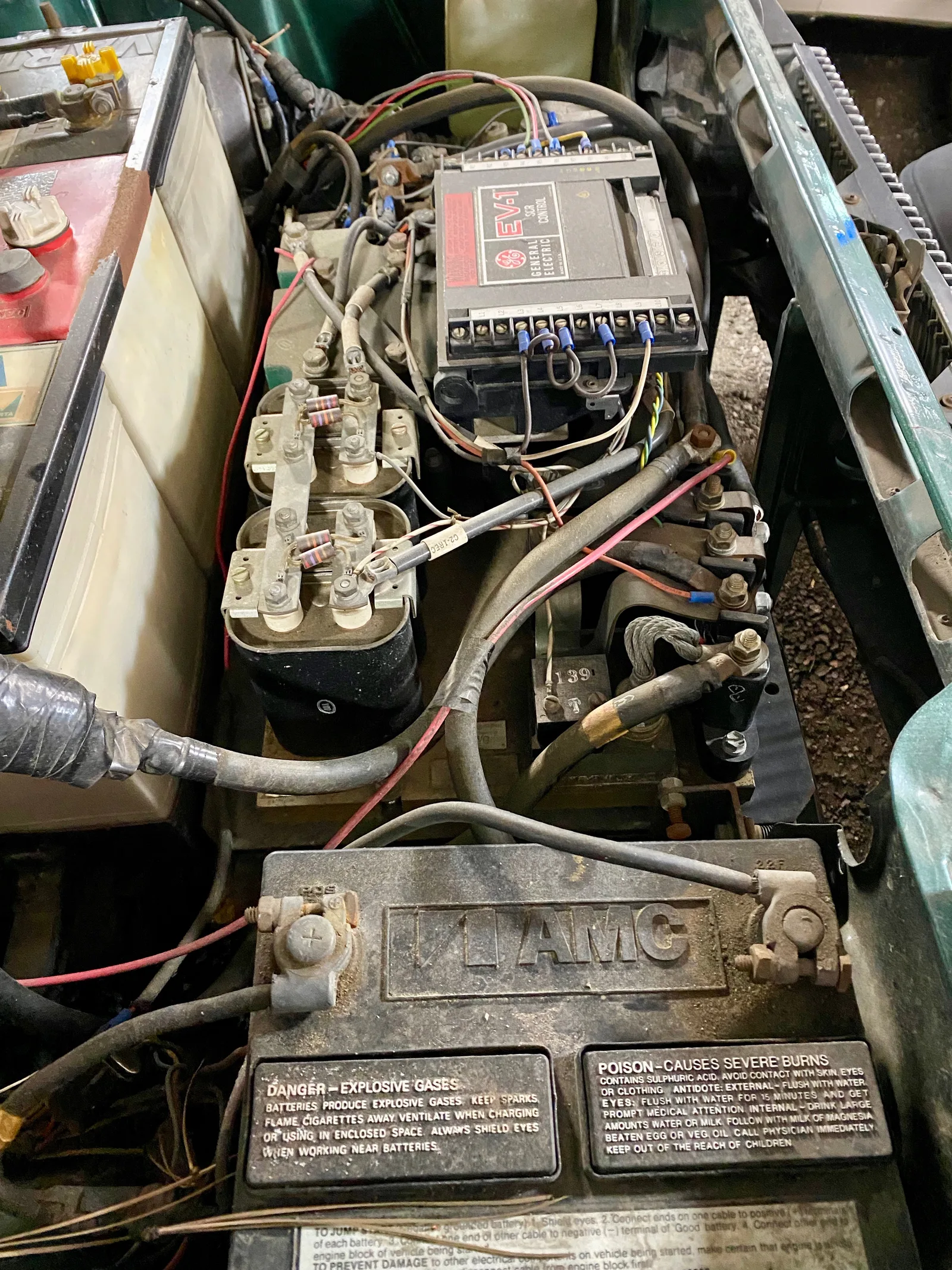 Gros plan sur le contrôleur électronique et les batteries d'un kit de conversion électrique installé sous le capot d'un véhicule ancien