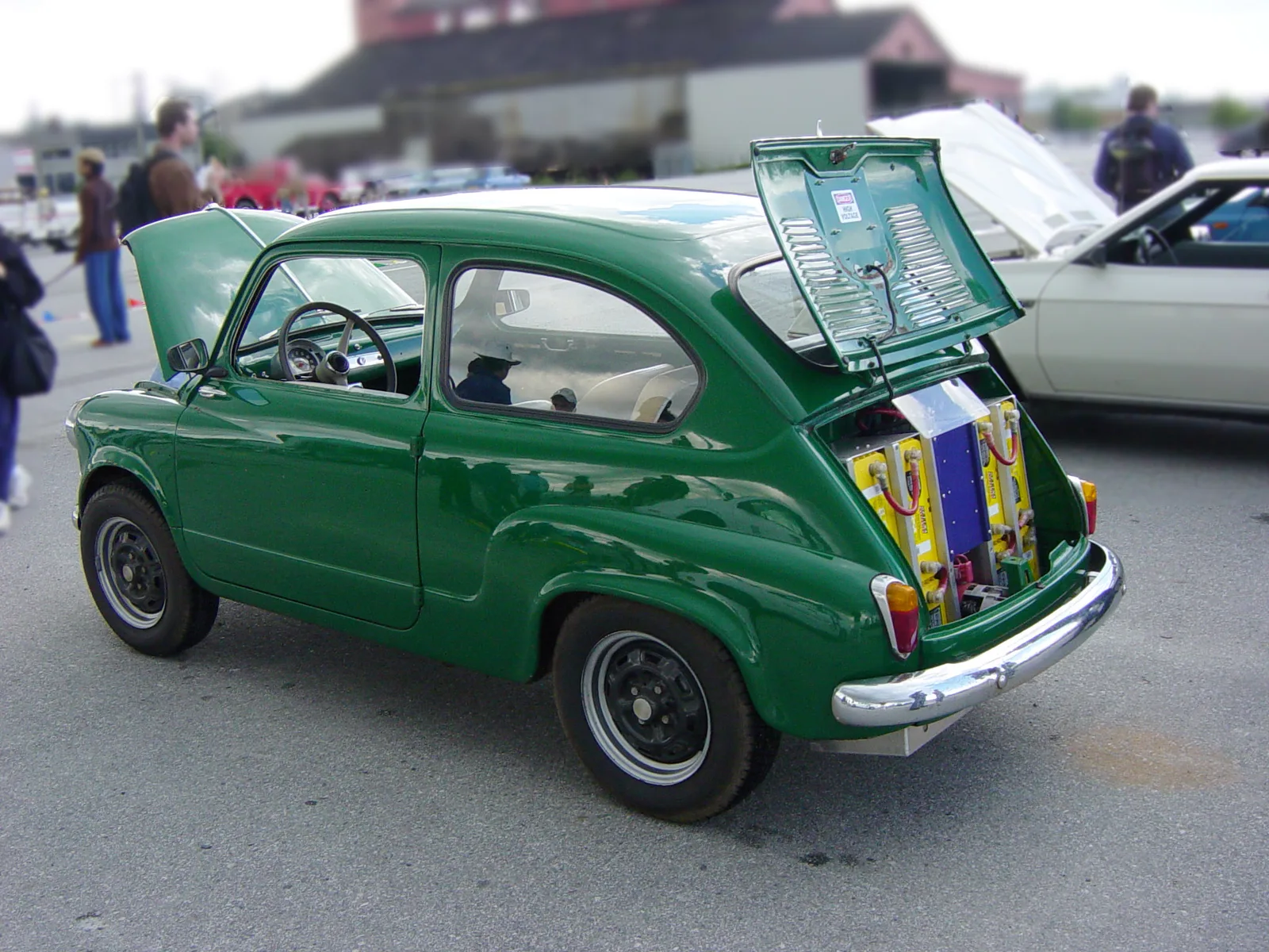 Fiat 600 ancienne convertie à l'électrique, coffre arrière ouvert montrant les packs de batteries jaunes et bleus installés