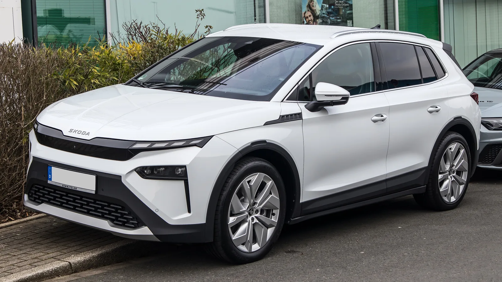 Skoda Elroq 85 blanc vu de trois quarts avant sur un parking, SUV électrique compact capable de tracter 1 800 kg