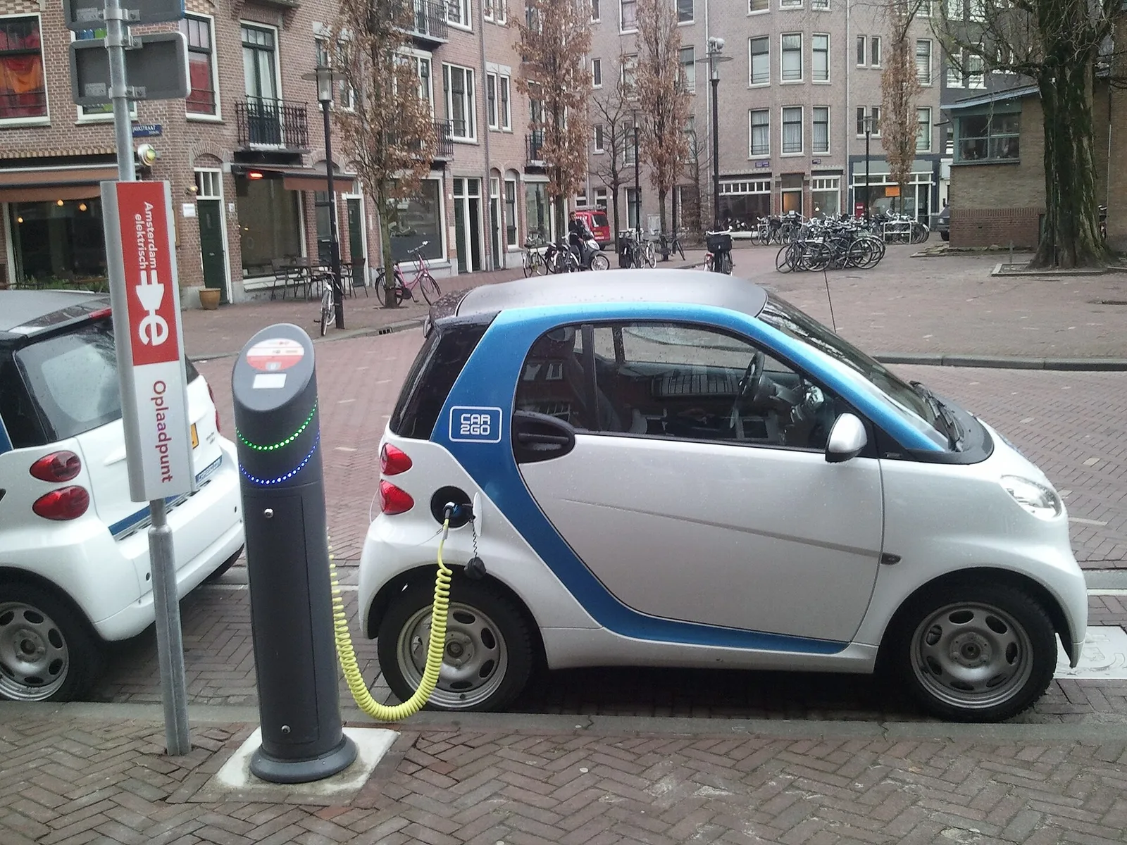 Smart électrique blanche et bleue en recharge sur une borne publique à Amsterdam