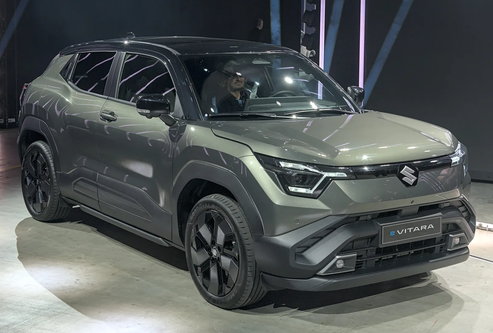 Suzuki e-Vitara 2026 vue de profil SUV électrique gris sur un salon automobile