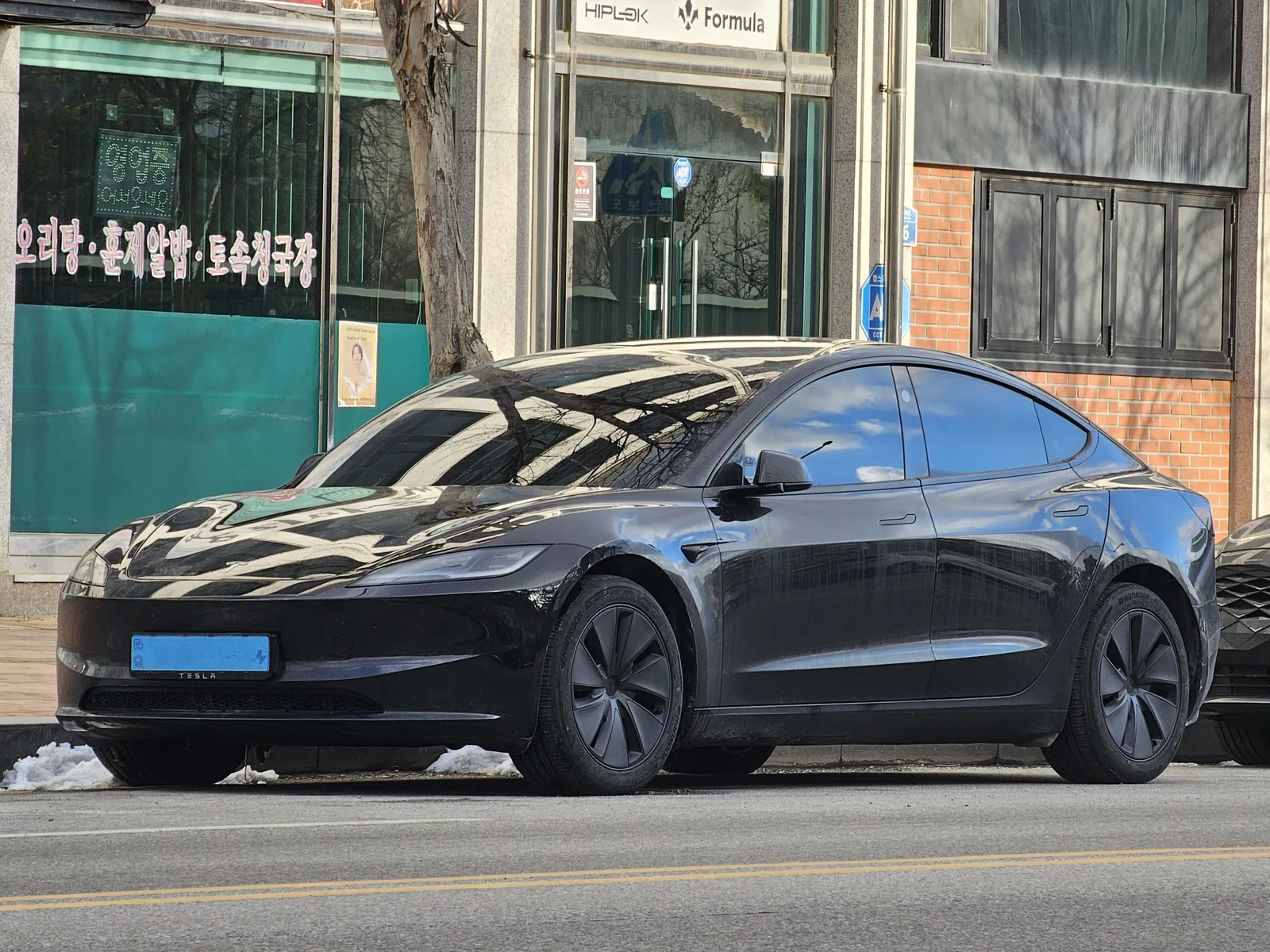 Tesla Model 3 Highland noire garée en ville, voiture électrique qui consomme le moins en 2026