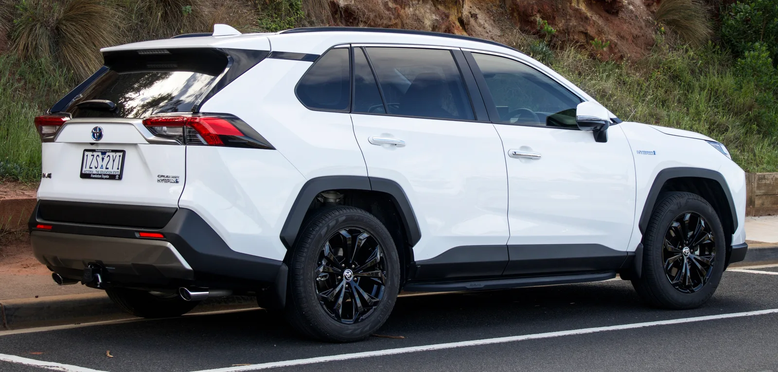 Toyota RAV4 hybride 2026 vue arrière profil droit badge Hybrid blanc SUV